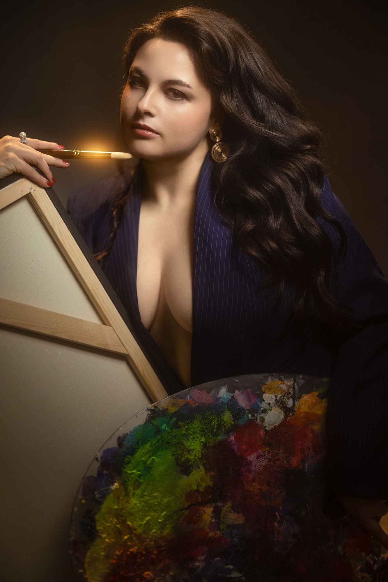 Woman in a navy blazer holding a paintbrush and palette during a creative boudoir portrait session near South Bend, Indiana