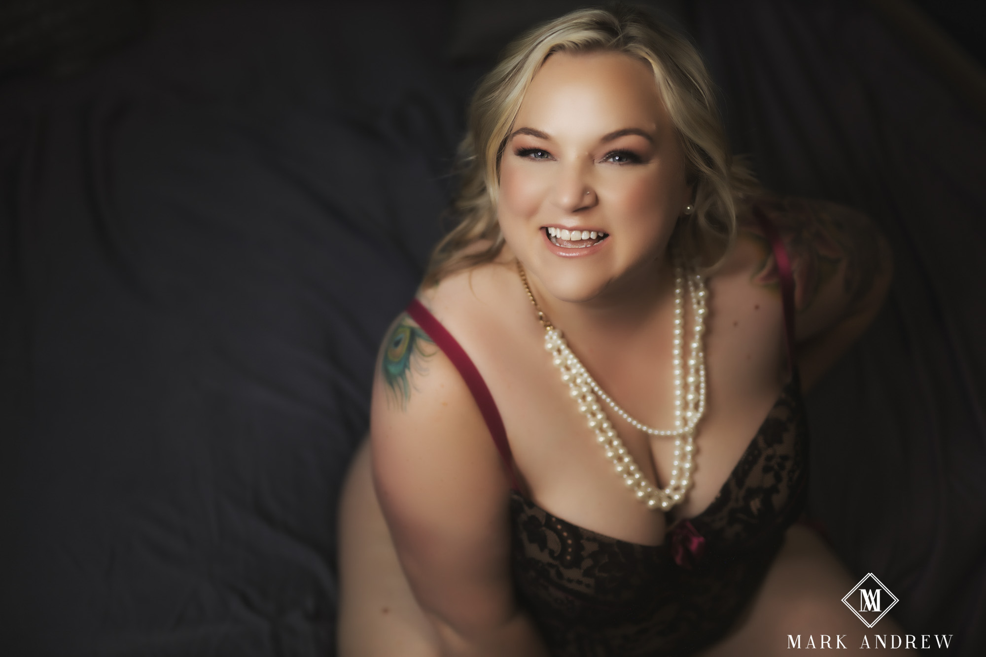 Becky in dark lace and pearl necklace, joyful smile, laying pose — luxury boudoir portrait, Mishawaka Indiana studio