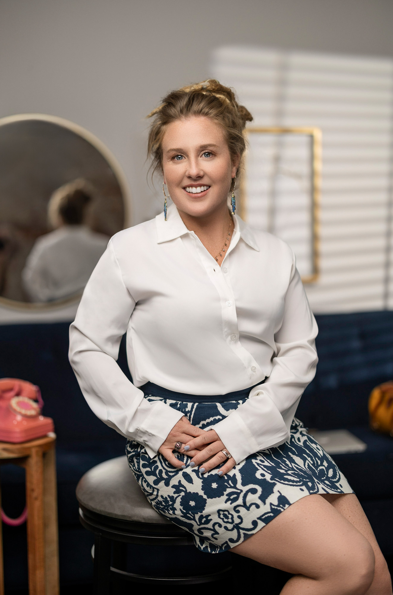 Heidi in a white silk shirt and blue floral skirt with vintage props and round mirror — editorial realtor branding portrait, Beaufort SC