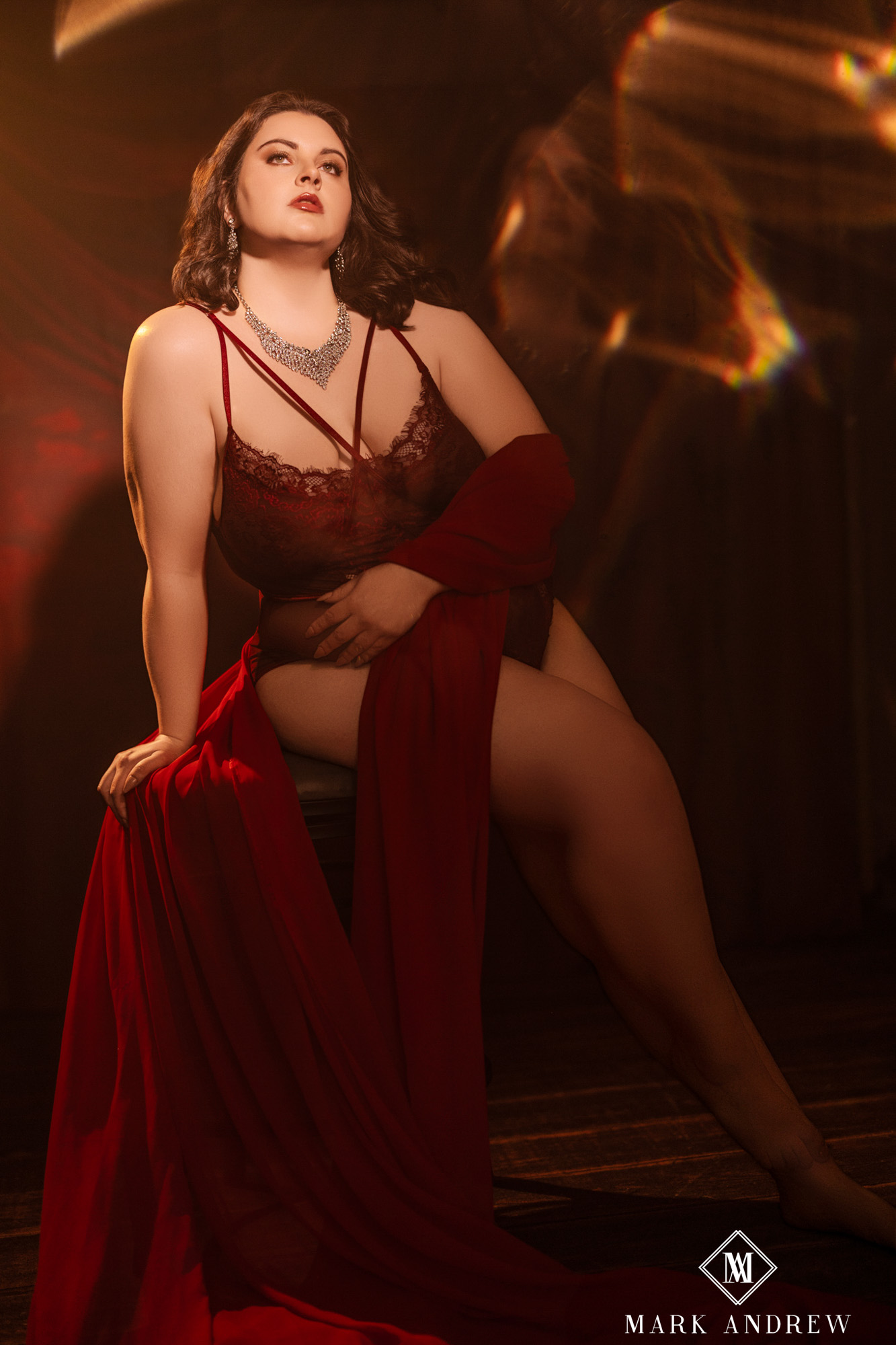 Katherine seated with a flowing red drape against warm theatrical light — the kind of frame she described as 'a glamorized version of myself'