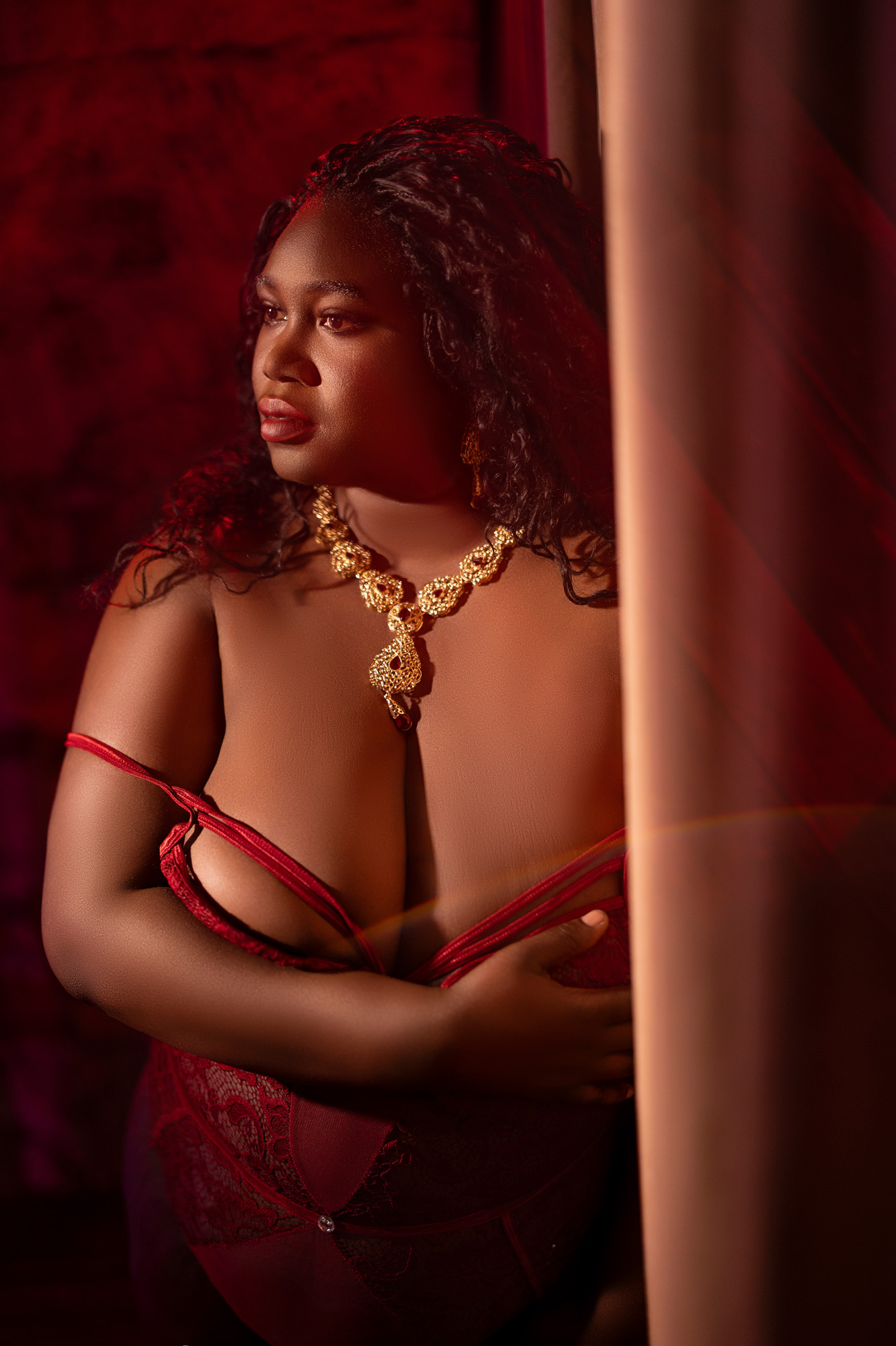 Boudoir client in red lace lingerie with warm dramatic light