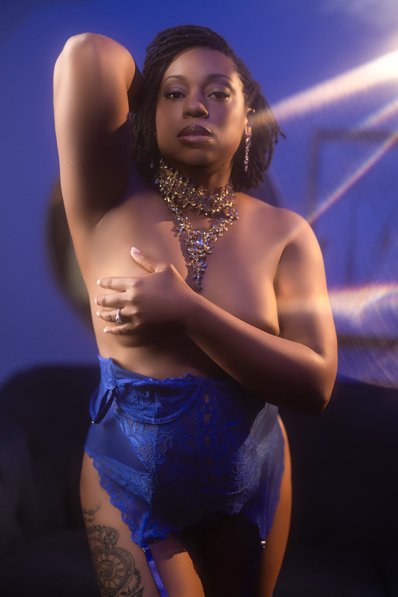 Boudoir client in royal blue lace lingerie under cool neon light