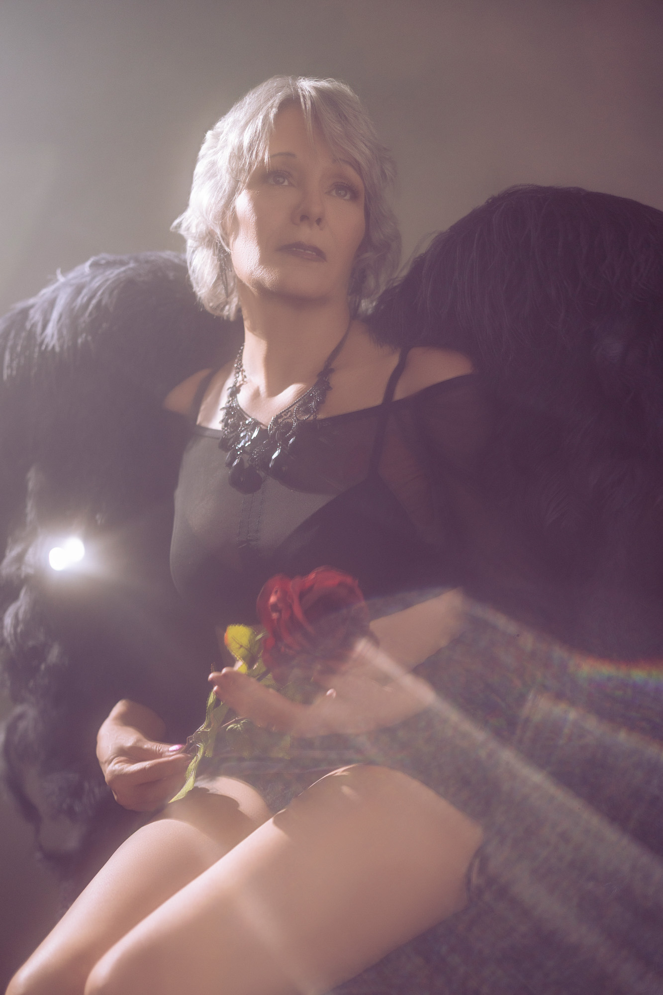Boudoir client with professionally styled silver hair, black mesh, and roses — full-glam camera-ready look