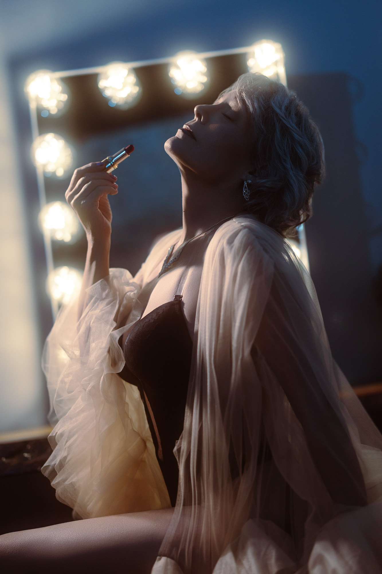 Boudoir client in cream velvet bra and tulle robe at vanity