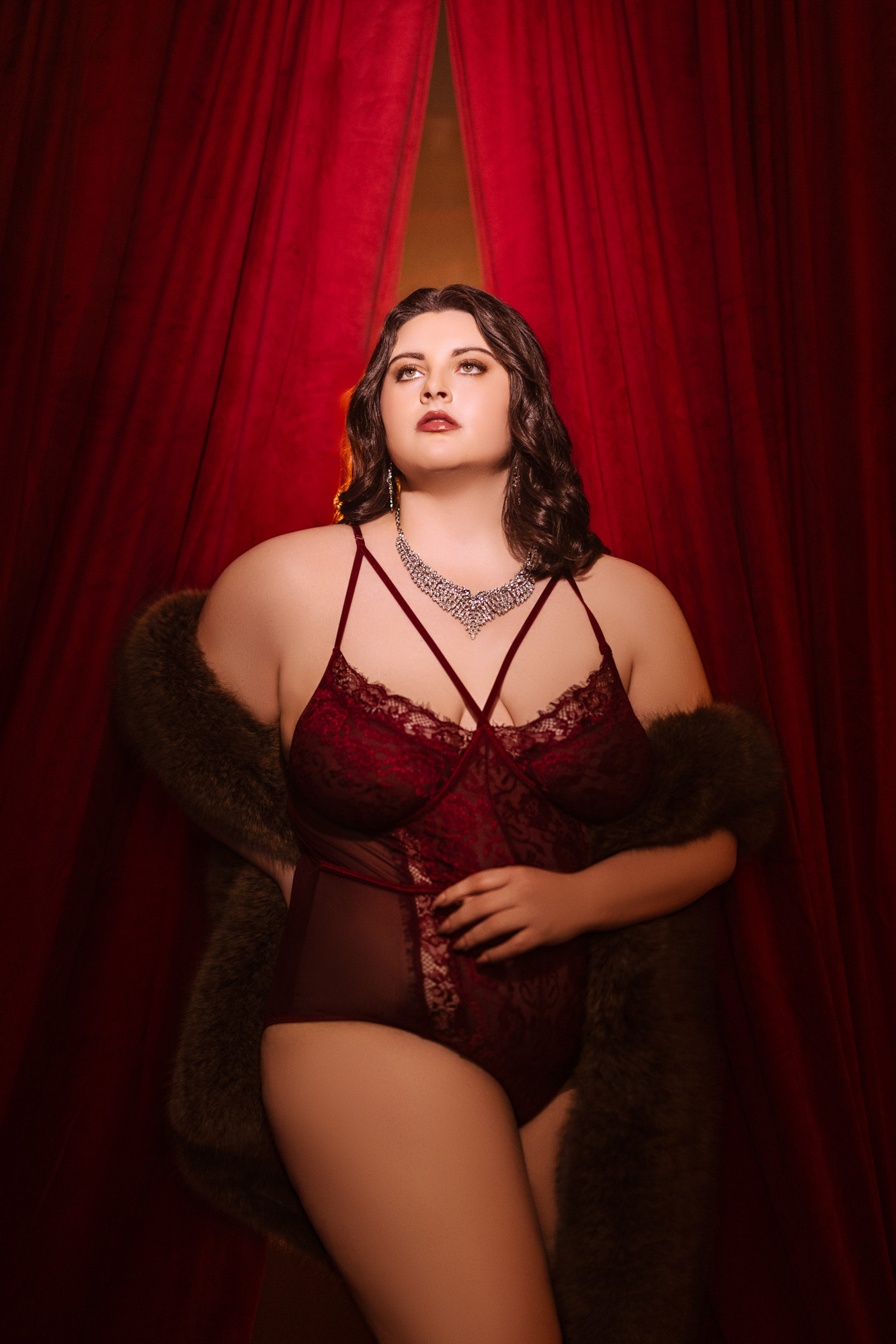 Boudoir client in wine lace bodysuit, fur coat, and diamond necklace — the bodysuit-over-babydoll example